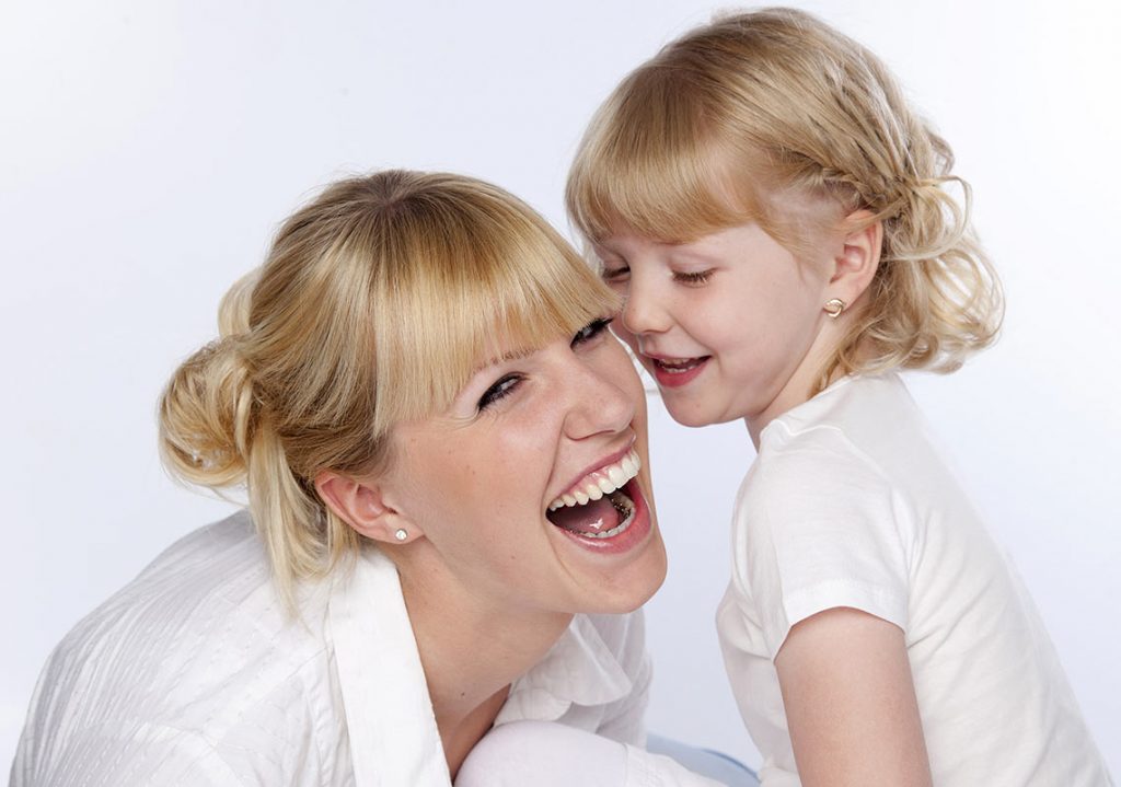 Eine Frau mit einer Incognito™ Zahnspange und ein kleines Mädchen lachen zusammen.