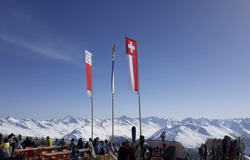 Auf einem Berggipfel in der Schweiz sind mehrere Flaggen zu sehen.